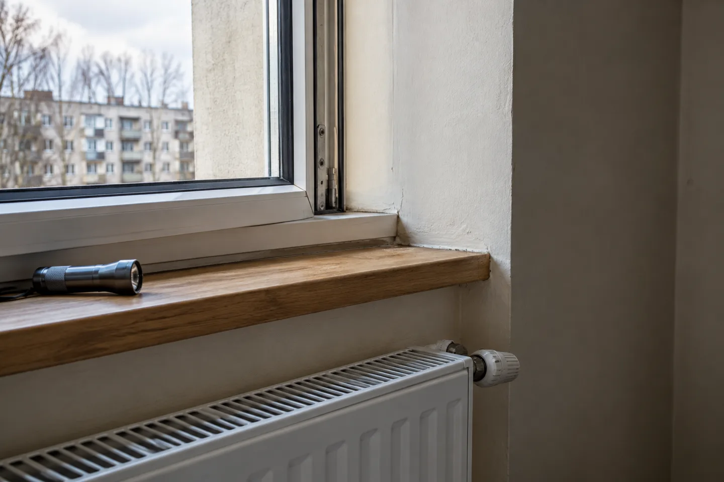 Apartment window joints, sill and radiator to check during a pre-purchase inspection.